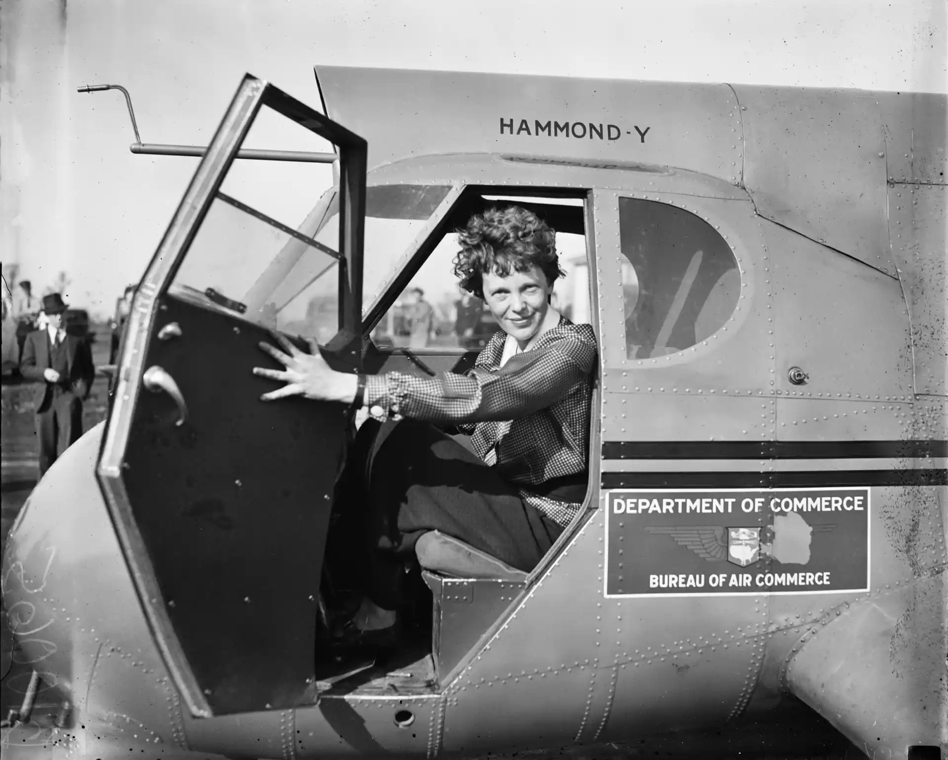 Black-and-white archival photograph of Amelia Earhart seated in an airplane in 1936